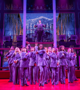 Bryce Pinkham as The Arbiter and the cast of Chess.
© Matthew Murphy